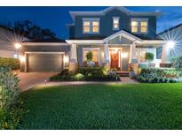 Charming two-story home featuring a lush green lawn, manicured landscaping, and inviting front porch at twilight at 3106 W Bay Villa Ave, Tampa, FL 33611