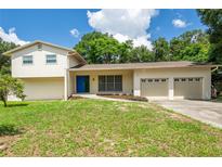 Inviting two-story home with a well-manicured lawn and a vibrant blue front door at 514 Crestover Dr, Temple Terrace, FL 33617