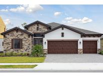 Charming single-story home featuring a stone facade, three-car garage, and well-manicured lawn at 13110 Homestead Ln, Parrish, FL 34219