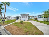 Cute light blue manufactured home with carport and landscaped lawn at 122 E Saint Johns Way, Apollo Beach, FL 33572