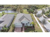 Single-Gathering home with grey roof, light green exterior, and brick driveway at 212 Shell Creek Ct, Apollo Beach, FL 33572