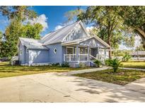 Charming light blue house with a metal roof, porch, and a spacious concrete driveway at 106 E Calhoun St, Plant City, FL 33563
