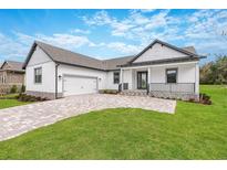 Modern farmhouse exterior with gray and white color scheme, two car garage, and paved driveway at 4555 Hickory Oak Dr, Brooksville, FL 34601