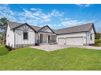 Modern two-story home with three car garage and manicured lawn at 6773 Summit View Dr, Brooksville, FL 34601