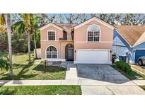 Two-story house with a peach-colored exterior, attached garage, and a small front yard at 6702 Mirror Lake Ave, Tampa, FL 33634