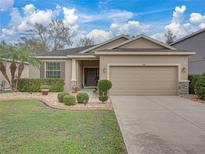 Tan house with two car garage and landscaped yard at 8518 Tidal Breeze Dr, Riverview, FL 33569