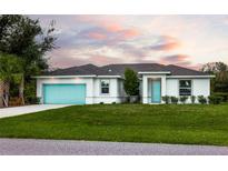 Newly built home with teal garage door and manicured lawn at 411 Seasons Dr, Punta Gorda, FL 33983