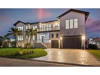 Elegant two-story home with a paved driveway, lush lawn, and a three-car garage at twilight at 1954 Iowa Ne Ave, St Petersburg, FL 33703