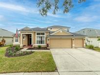 Two-story house with tan exterior, three-car garage, and manicured lawn at 2622 Bonterra Blvd, Valrico, FL 33594