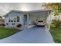 Light blue manufactured home with carport and landscaped lawn at 70 Pelican E Dr, Oldsmar, FL 34677