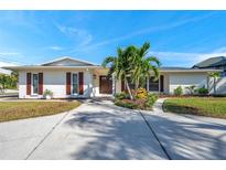 Charming single-story home featuring a well-manicured lawn, lovely landscaping and a spacious concrete driveway at 910 Oakwood Dr, Largo, FL 33770