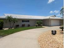 Spacious single-story home with a white tile roof, manicured lawn, and circular driveway at 212 Poinciana Ln, Largo, FL 33770