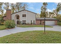 Two story house with brick and siding, attached garage, and landscaped lawn at 223 S Riverhills Dr, Temple Terrace, FL 33617