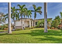 Charming single-story home with lush landscaping, a manicured lawn, and tropical palm trees in a sunny neighborhood at 815 3Rd S Ave, Tierra Verde, FL 33715