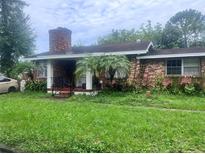 Brick house with a porch, palm trees, and a grassy lawn at 10006 N Mitchell Ave, Tampa, FL 33612