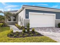 Exterior view of a single-story home with a two-car garage and landscaped walkway at 20345 Symphony Pl, Venice, FL 34293