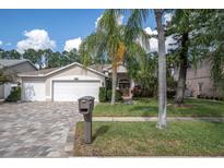 Two-car garage home with a paver driveway and a well-maintained lawn at 11401 Georgetown Cir, Tampa, FL 33635