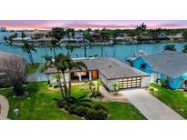 Inviting waterfront home featuring lush landscaping, a modern garage door, and serene water views at 11683 Grove St, Seminole, FL 33772