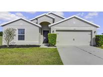 Single-story home with neutral exterior, two-car garage, and well-manicured lawn at 6731 Wirevine Dr, Brooksville, FL 34602