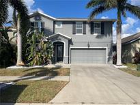 Two-story house with gray exterior, two-car garage, and landscaping at 12013 Whistling Wind Dr, Riverview, FL 33579