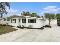 Charming single-story home with white exterior, manicured landscaping, and a spacious driveway at 6317 S Lansdale Cir, Tampa, FL 33616