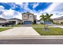 Two-story house with gray siding, blue garage doors, and landscaping at 11834 Brighton Knoll Loop, Riverview, FL 33579