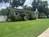 Charming one-story home with a well-maintained lawn and landscaped with decorative tropical plants and mature trees at 1003 W Mahoney St, Plant City, FL 33563