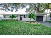 Charming single-story home with lush green landscaping and a dark driveway at 13480 Twig Ter, Largo, FL 33774