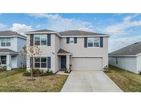 Two-story home with a two-car garage, blue shutters, and a landscaped front yard at 37127 Goffaux Loop, Zephyrhills, FL 33541