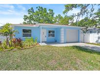 Charming, light blue single-story home with an attached garage and a well-manicured front lawn at 615 W Virginia Ave, Tampa, FL 33603