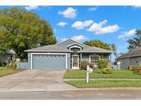 One-story home with gray exterior, two-car garage, and landscaping at 13229 Golf Ridge Pl, Hudson, FL 34669