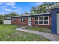 Brick ranch home with blue accents and a well-maintained lawn at 12905 N Oregon Ave, Tampa, FL 33612