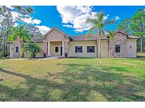 Tan house with stone accents, tile roof, and palm trees at 5403 Golddust Rd, Spring Hill, FL 34609