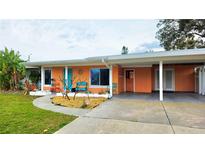 Charming single-story home featuring a vibrant exterior, covered parking, and well-maintained landscaping at 552 Trade Winds Dr, Dunedin, FL 34698