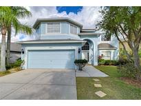 Two-story house with light blue exterior, two-car garage, and landscaped yard at 10816 Lakeside Vista Dr, Riverview, FL 33569