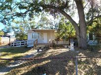 Tan house with white trim, ramp, and mature trees in the front yard at 1708 Preston S St, St Petersburg, FL 33712