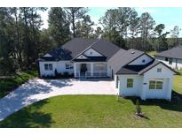 White two-story house with gray roof, stone driveway, and large backyard at 4675 Hickory Oak Dr, Brooksville, FL 34601