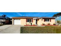 Charming single-story home featuring a manicured front lawn, attached garage, and decorative window shutters at 10863 112Th Pl, Largo, FL 33778