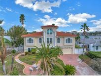Two-story waterfront home with red tile roof and palm trees at 30 Dolphin Dr, Treasure Island, FL 33706