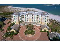 Stunning aerial view of a beachfront condo complex with beautiful landscaping, a circular driveway, and sandy beaches at 800 Collany Rd # 605 & 606, Tierra Verde, FL 33715