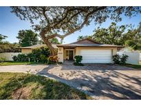 Single-story home with a large tree and a paved driveway at 1609 Lakeview Rd, Clearwater, FL 33756