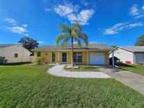 Cute yellow house with a palm tree, white rock pathway, and attached garage at 3141 Ludlow Dr, New Port Richey, FL 34655