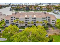 Aerial view of waterfront condo building with lush landscaping and boat slips at 6260 Kipps Colony Ct # 204, Gulfport, FL 33707