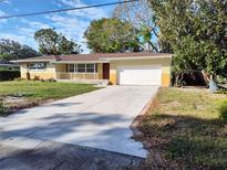 Ranch-style home with a large driveway, attached garage, and well-maintained lawn at 1182 Norwood Ave, Clearwater, FL 33756