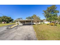 Ranch-style home with carport, mature trees, and a spacious yard at 11945 Carmen Ave, Dade City, FL 33525