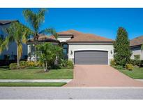 One-story home with gray garage door and brick driveway, surrounded by palm trees and lush landscaping at 12241 Perennial Pl, Bradenton, FL 34211