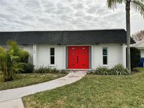 White single story home with a red front door and landscaped lawn at 3960 Headsail Dr, New Port Richey, FL 34652