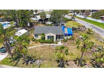 Aerial view of a one-story home with a gray roof, lush greenery, and a classic vintage truck nearby at 8474 Tobay N Rd, St Petersburg, FL 33702