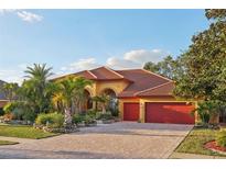 Stunning Spanish style home with red tile roof, lush landscaping, and two-car garage at 3921 Mimosa Pl, Palm Harbor, FL 34685