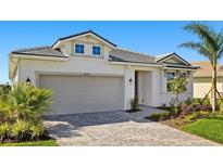 Charming single-story home featuring a gray tiled roof, a two-car garage, and neatly landscaped grounds at 12241 Meditation Trl, Venice, FL 34293